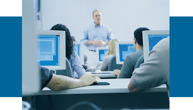 A group of people sitting at tables with computers.