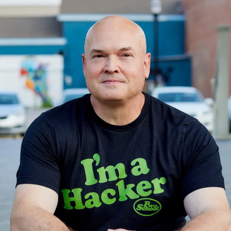 A bald man with a black shirt and green letters on it